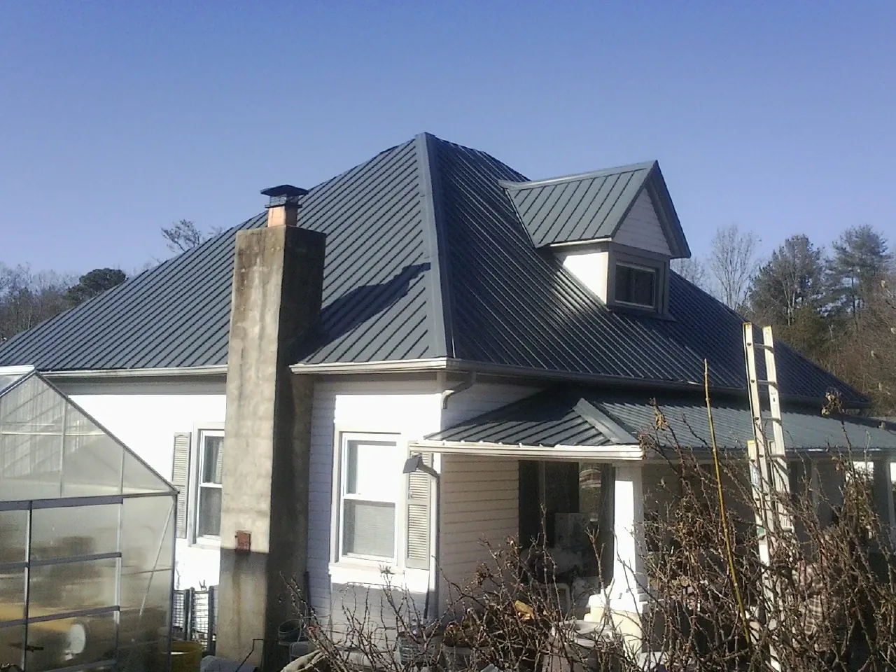 Dark blue standing seam metal roof on a white farmhouse with dormer — Slate & Tile Roof Repair by Roofing Brothers in Champaign