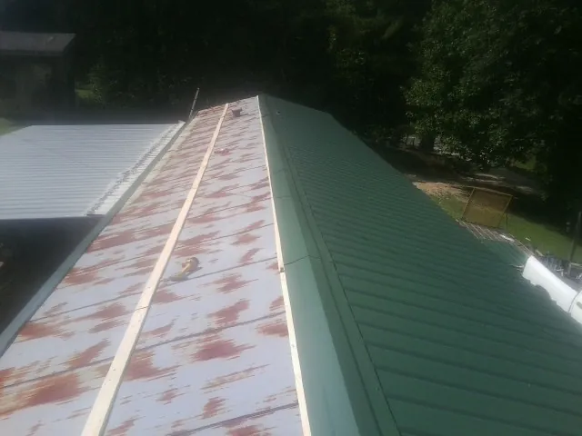 Old rusted panels beside newly installed green metal roofing — Wind Damage Roof Repair by Roofing Brothers in Champaign