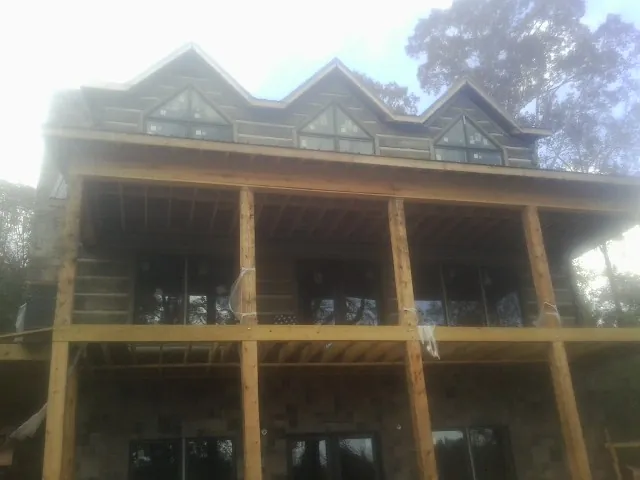 Dormers and porch framing on a large log home under construction — Roof Coating work by our crew in Champaign