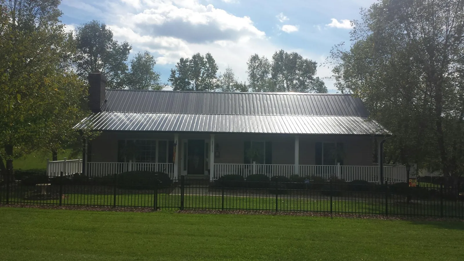 Gray metal roof on a brick ranch with a full width front porch — Gutter Guard Installation work by our crew in Champaign