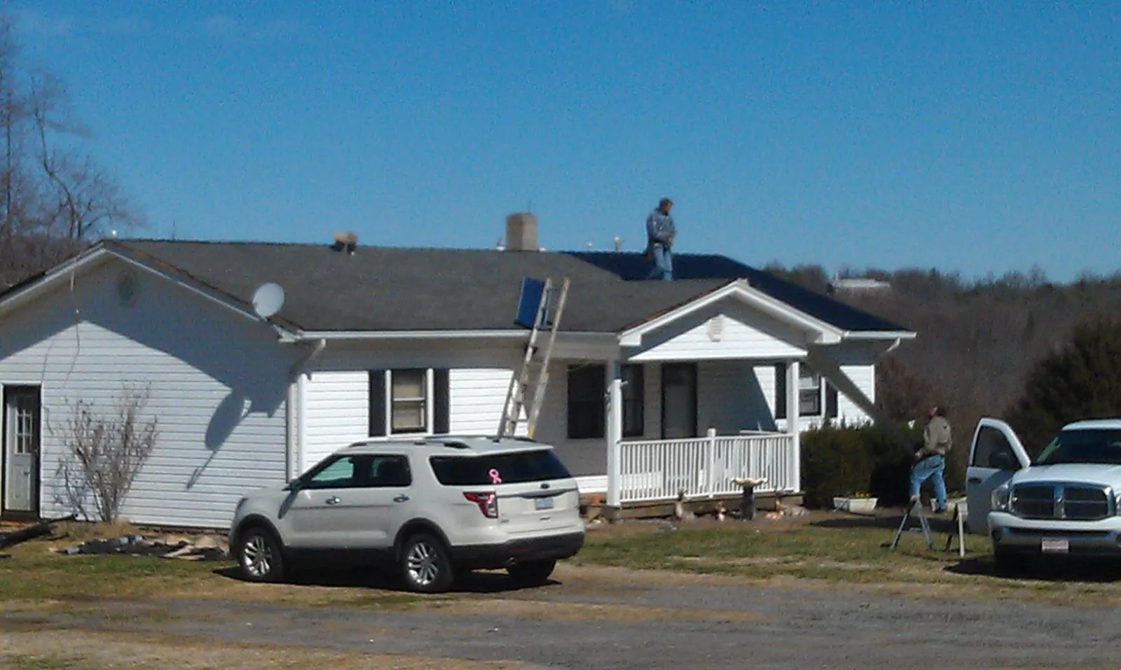 Roofers stripping shingles from a white ranch house roof in Champaign