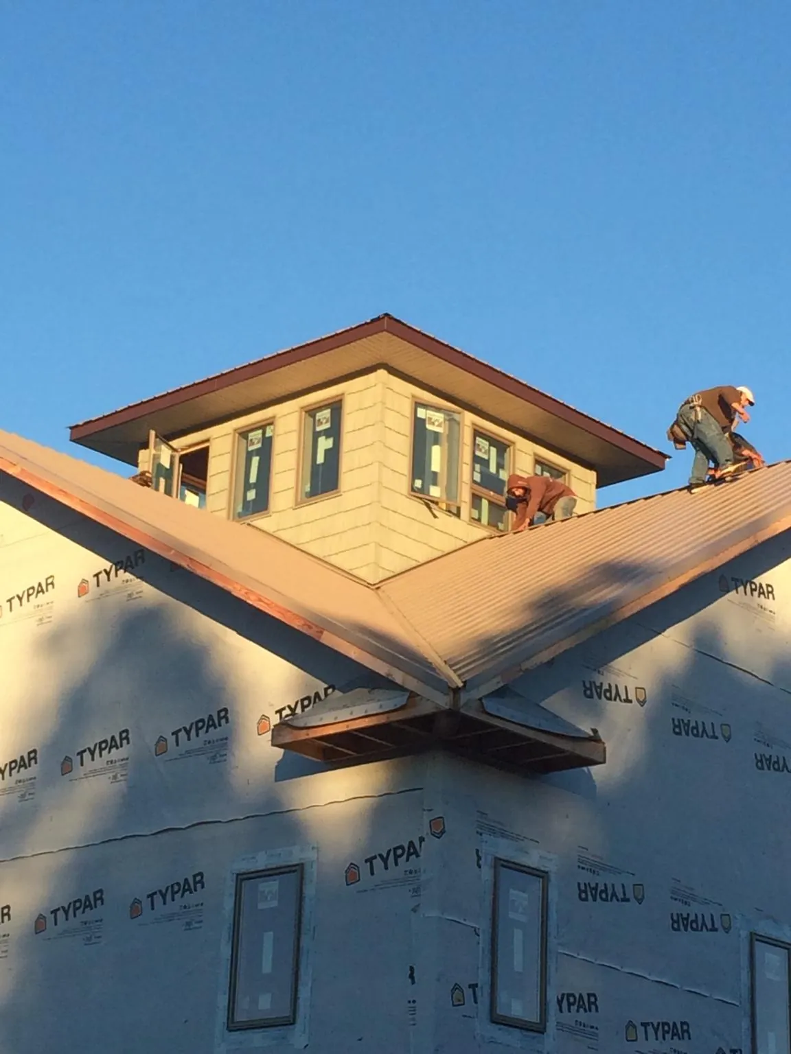 Roofers working around a rooftop cupola on a new metal roof at sunset — Roof Waterproofing in Champaign by Roofing Brothers